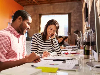 Colleagues discussing printed documents at desk